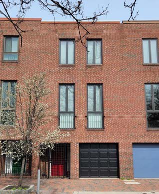 1007 Lombard Street, a 1978 brick rowhouse with a garage door at the pavement