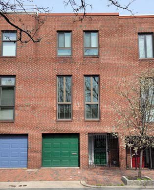 1009 Lombard Street, a 1978 brick rowhouse with a green garage door