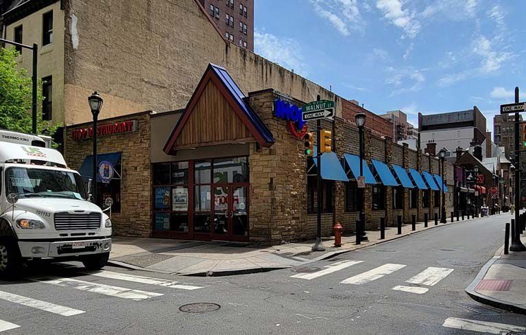 The nomination's photograph of 1320-22 Walnut Street: a one-story IHOP with blue awnings at the corner of Juniper Street